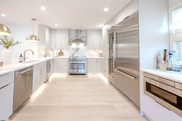 a large white kitchen with a stove a sink a refrigerator and a stove top oven