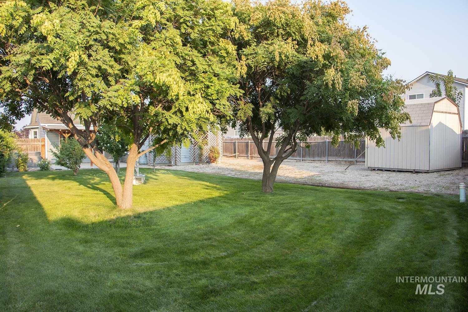 16559 Bayou Way Caldwell, ID 83607 - Photo 18 of 20 Expansive backyard featuring a manicured lawn, two mature trees, and a functional storage shed