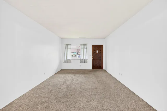 a view of an empty room with wooden floor and windows