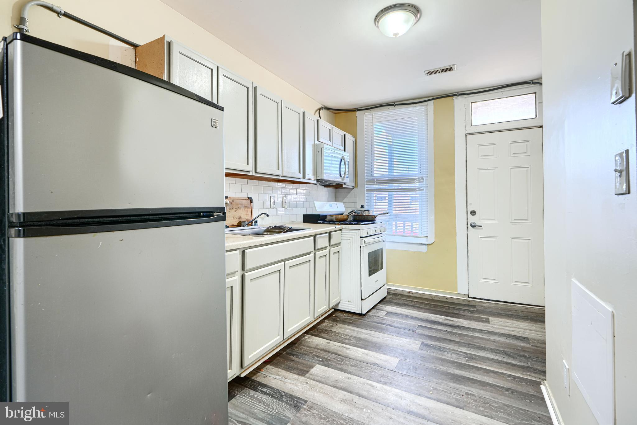 3218 Belair Road Baltimore, MD 21213 - Photo 13 of 26 a kitchen with white cabinets and white appliances
