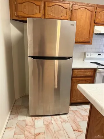 a view of a refrigerator in kitchen and an empty room
