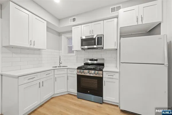 a kitchen with white cabinets and stainless steel appliances