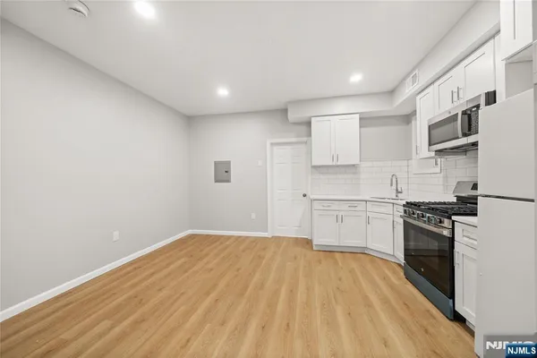 a kitchen with granite countertop white cabinets stainless steel appliances and wooden floor