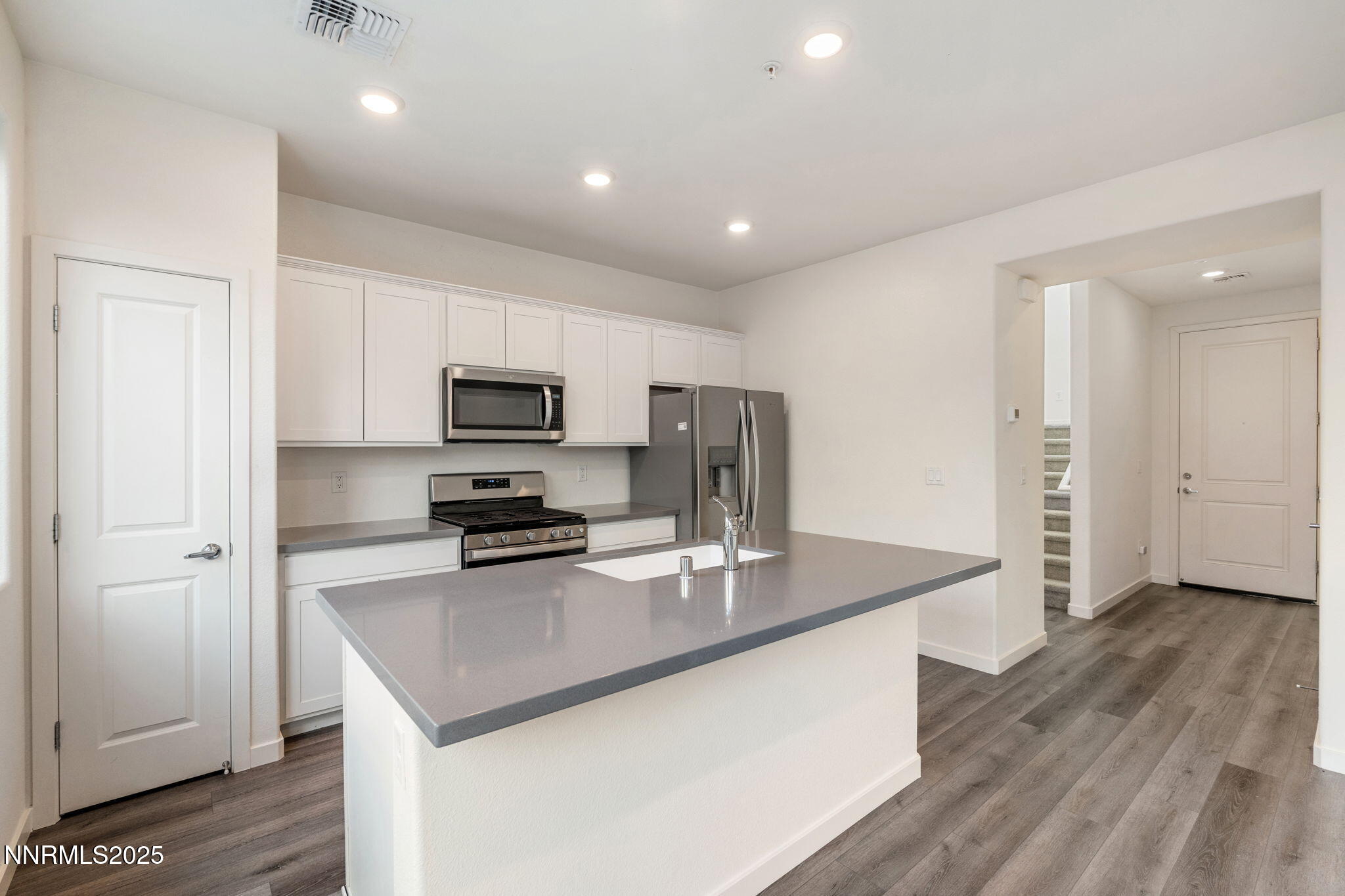 4589 Falcon Rock Lane Sun Valley, NV 89433 - Photo 7 of 26 a kitchen with stainless steel appliances granite countertop a sink a stove a refrigerator a sink a stove with wooden floor and cabinets