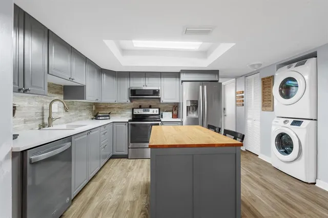 a kitchen with kitchen island granite countertop wooden cabinets stainless steel appliances and a sink