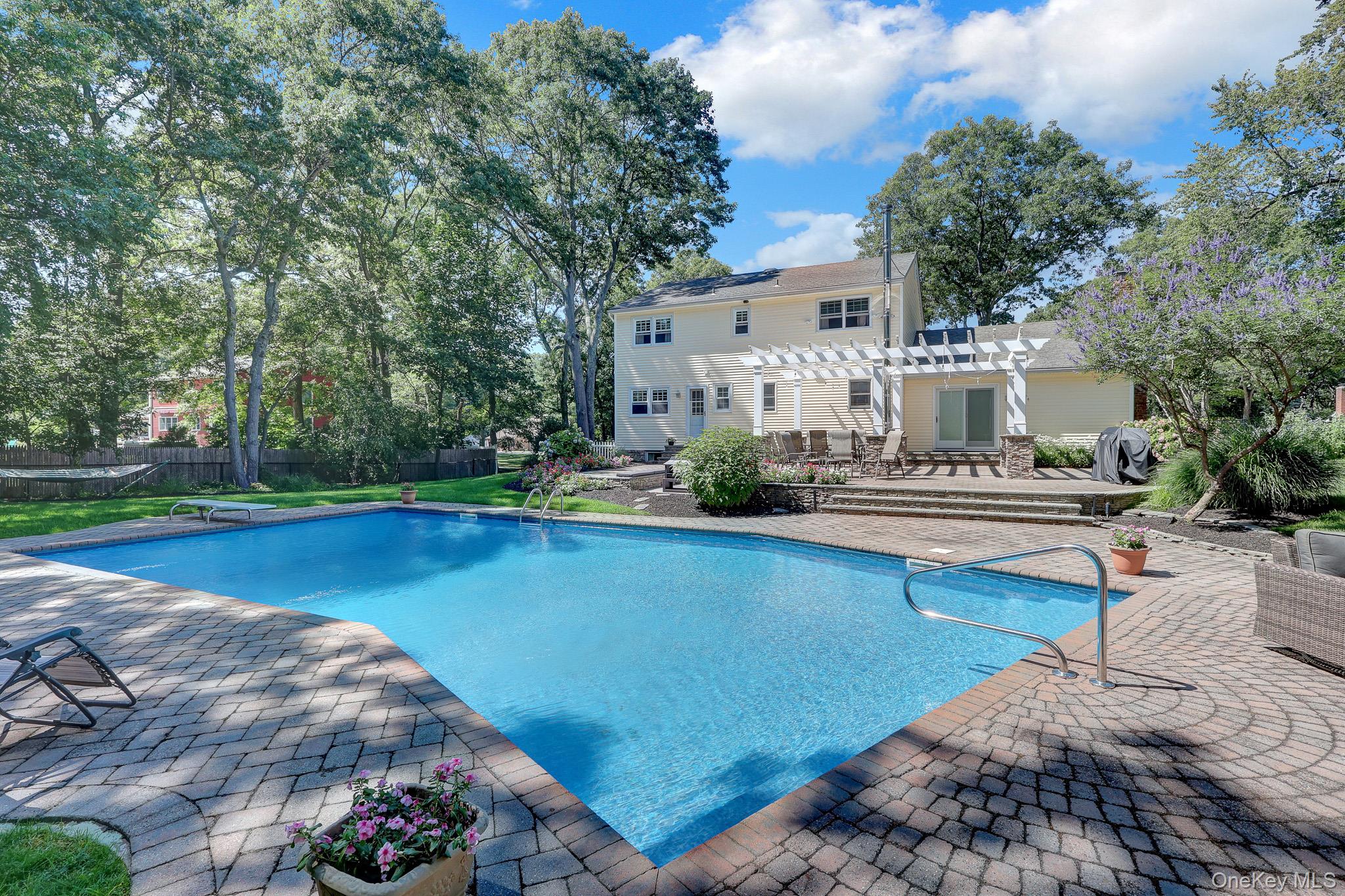 24 Fox Road East Setauket, NY 11733 - Photo 41 of 48 Expansive outdoor living area featuring a rectangular swimming pool, brick paver patio, and a pergola-covered patio with a sliding glass door