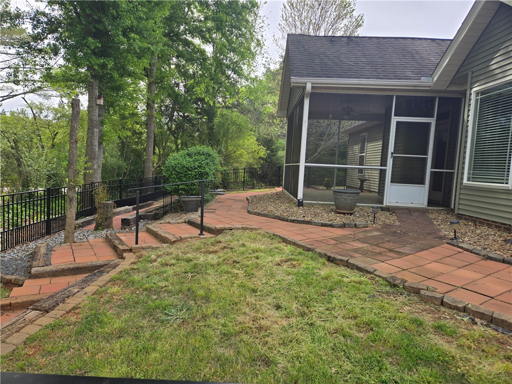 304 Knoll View Drive Seneca, SC 29678 - Photo 34 of 36 A well-maintained brick pathway gracefully winds through the lush yard, leading to a charming screened porch.