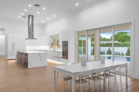 a kitchen with stainless steel appliances kitchen island granite countertop a table chairs sink and cabinets