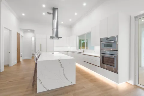 a large kitchen with stainless steel appliances kitchen island granite countertop a refrigerator and a stove top oven