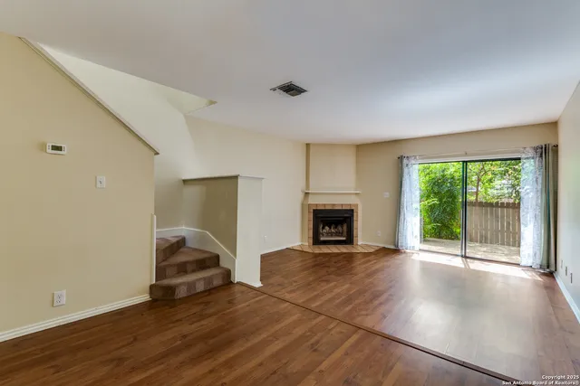 a view of empty room with wooden floor and fireplace