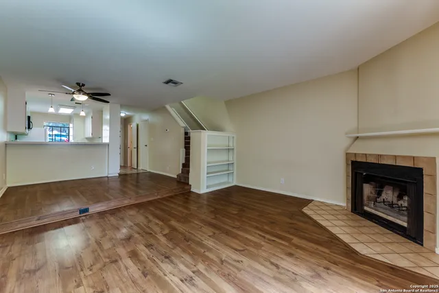 a view of an empty room with wooden floor fireplace and a window