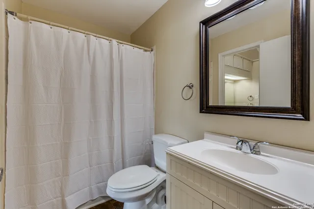 a bathroom with a granite countertop toilet sink and mirror