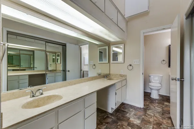 a spacious bathroom with a granite countertop sink toilet and mirror