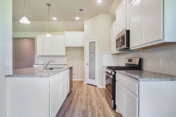 a kitchen with stainless steel appliances granite countertop a sink stove and refrigerator