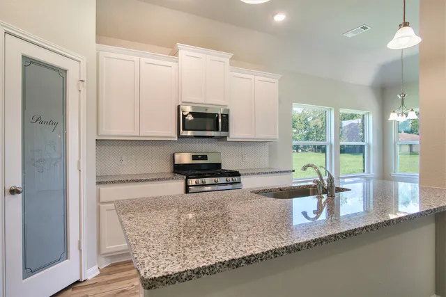 a kitchen with granite countertop a sink a counter top space and cabinets