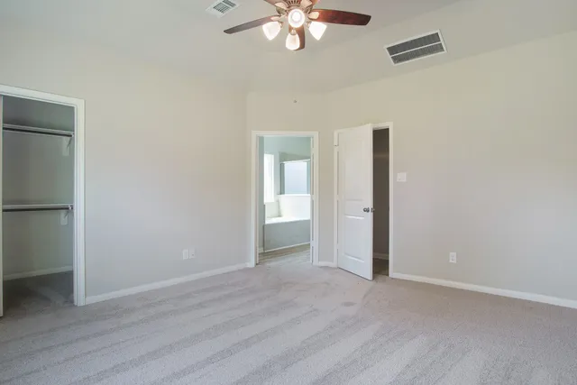 a view of an empty room with wooden floor and a ceiling fan