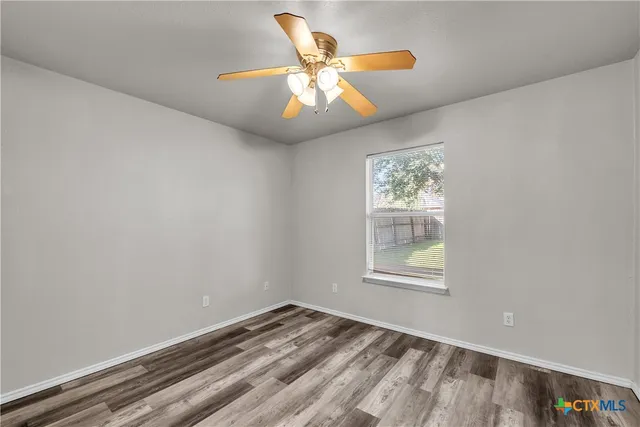 an empty room with window and ceiling fan