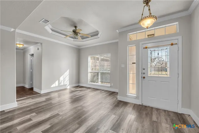 a view of an empty room with a window and wooden floor