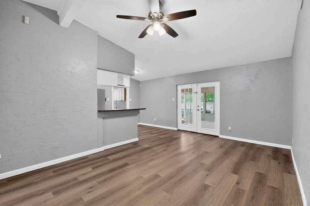 2309 Fyke Road Carrollton, TX 75006 - Photo 11 of 40 Spacious living area featuring wood-finish flooring, a ceiling fan with integrated lighting, and a white trim baseboard