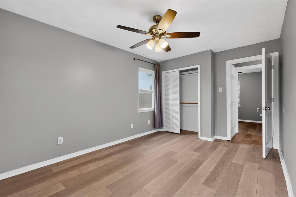 2309 Fyke Road Carrollton, TX 75006 - Photo 19 of 40 Bedroom featuring wood-finish flooring, a ceiling fan with integrated lighting, a window with natural light, and a closet with bi-fold doors