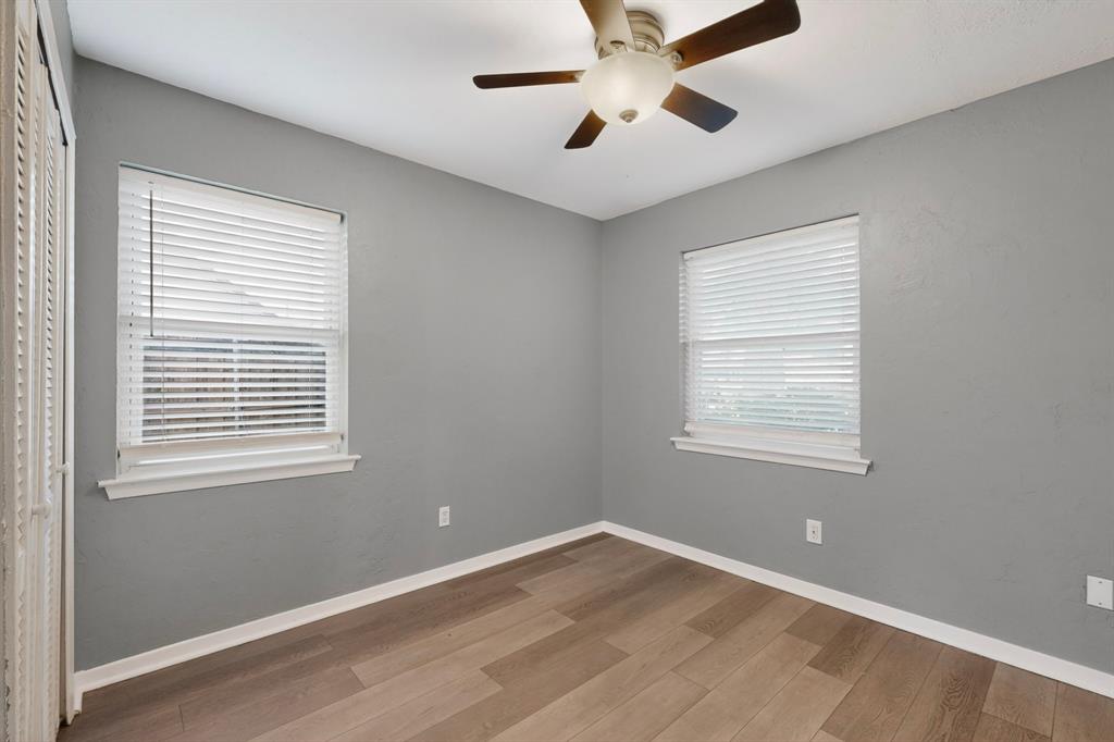 2309 Fyke Road Carrollton, TX 75006 - Photo 23 of 40 Room featuring wood-finish flooring, two windows with blinds, a ceiling fan with integrated lighting, white baseboards, and a bi-fold closet door