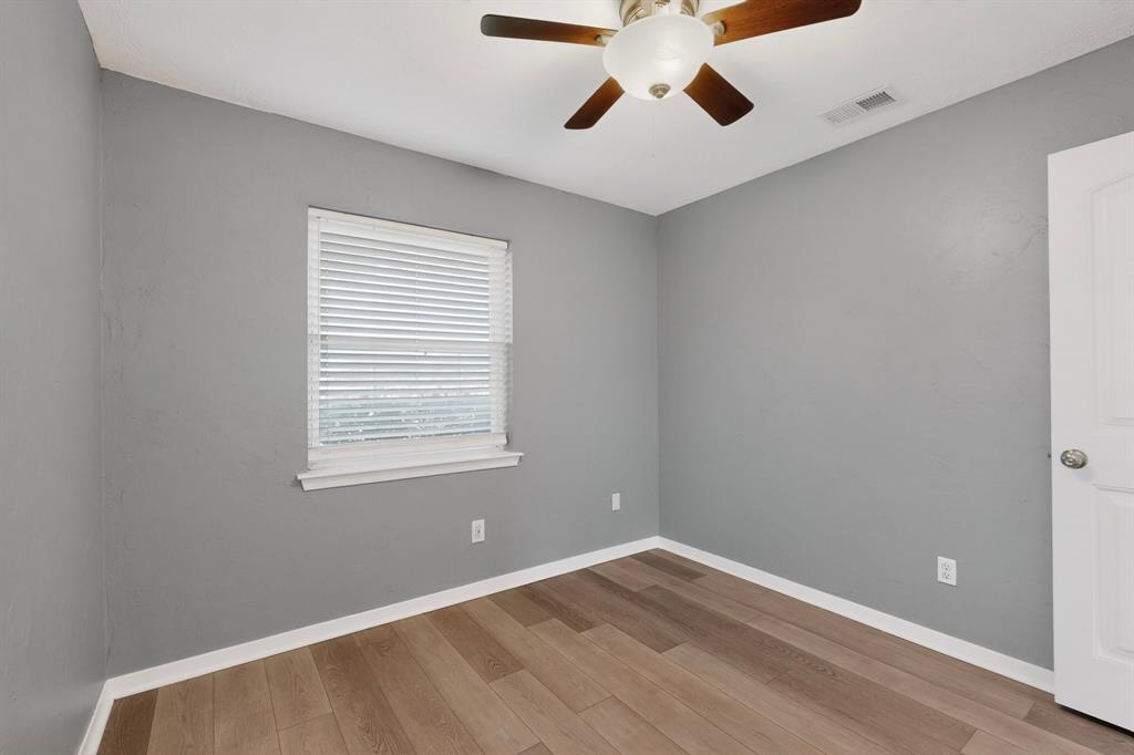 2309 Fyke Road Carrollton, TX 75006 - Photo 24 of 40 Room featuring wood-finish flooring, light gray walls, a ceiling fan with integrated lighting, and a white-trimmed window with blinds