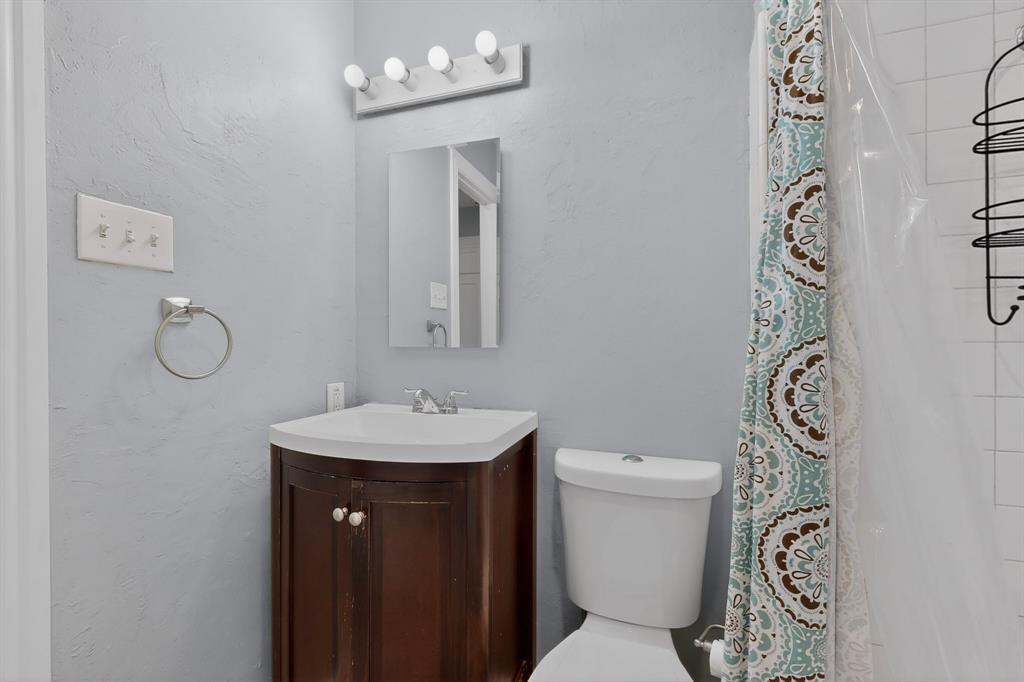 2309 Fyke Road Carrollton, TX 75006 - Photo 27 of 40 Compact bathroom featuring a corner vanity with a white countertop and dark wood-finish cabinetry