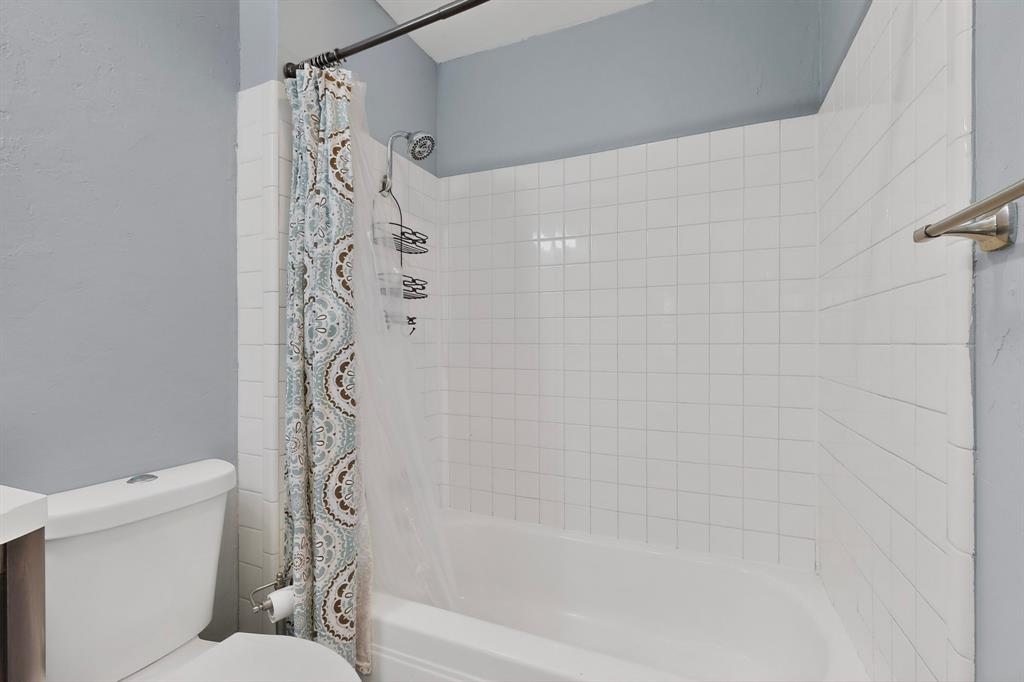 2309 Fyke Road Carrollton, TX 75006 - Photo 28 of 40 Bathroom featuring a white bathtub, white subway tile surround, showerhead, and a towel bar