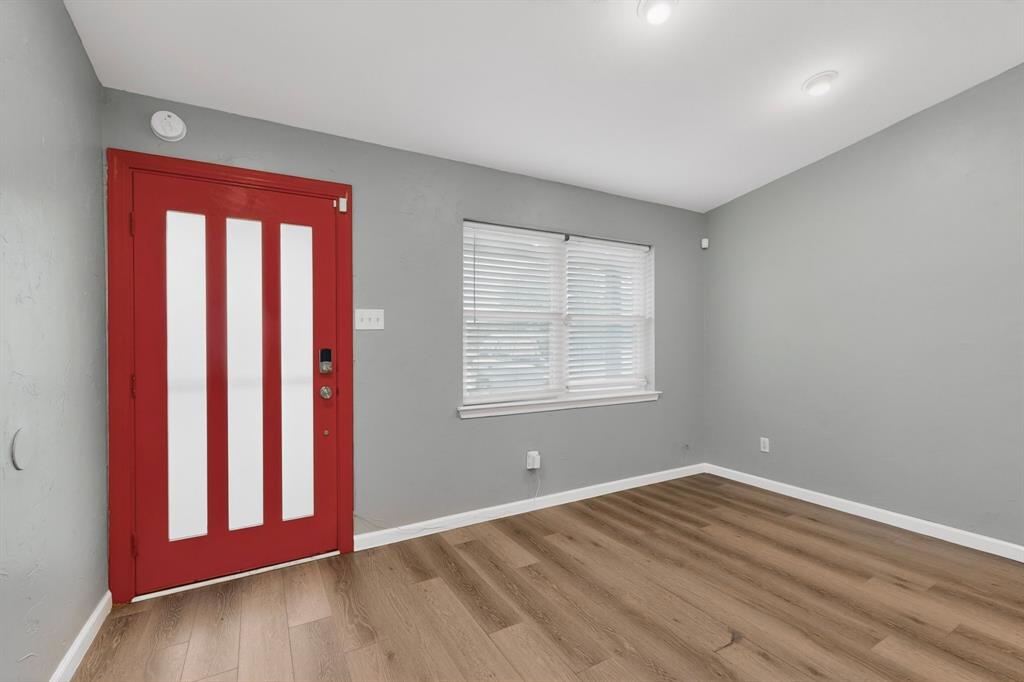2309 Fyke Road Carrollton, TX 75006 - Photo 5 of 40 Entryway featuring a bold red door with vertical glass panels, wood-finish flooring, and light gray walls