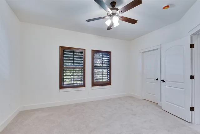 an empty room with chandelier fan and windows