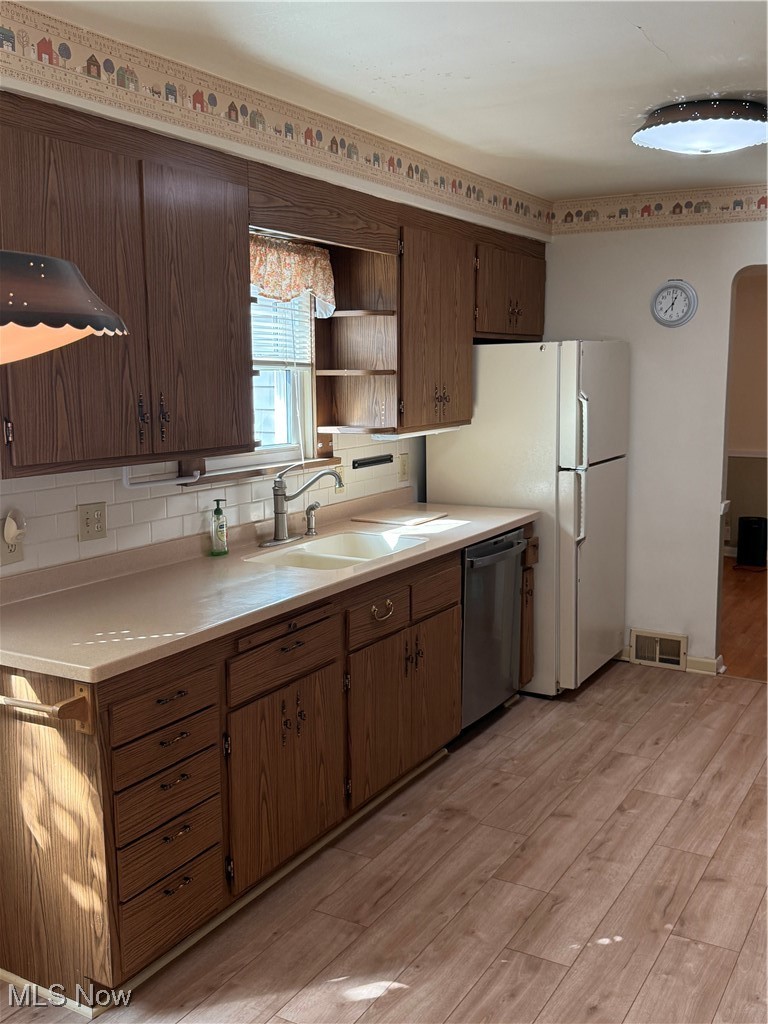 1284 Haverston Road Lyndhurst, OH 44124 - Photo 21 of 43 Kitchen featuring light countertops, light wood finished floors, arched walkways, tasteful backsplash, and dishwashing machine