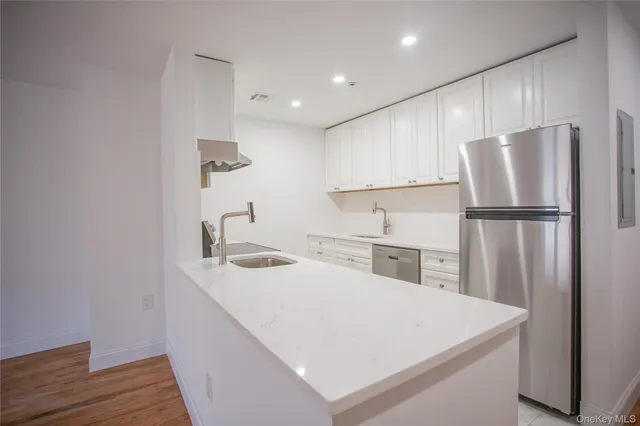 a kitchen with a sink a refrigerator and wooden floor