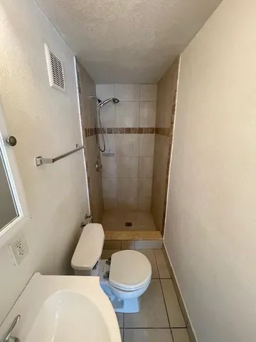 a white toilet sitting next to a bathroom sink and a shower