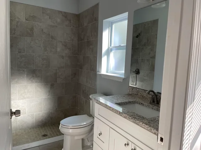 a bathroom with a granite countertop sink a toilet and shower
