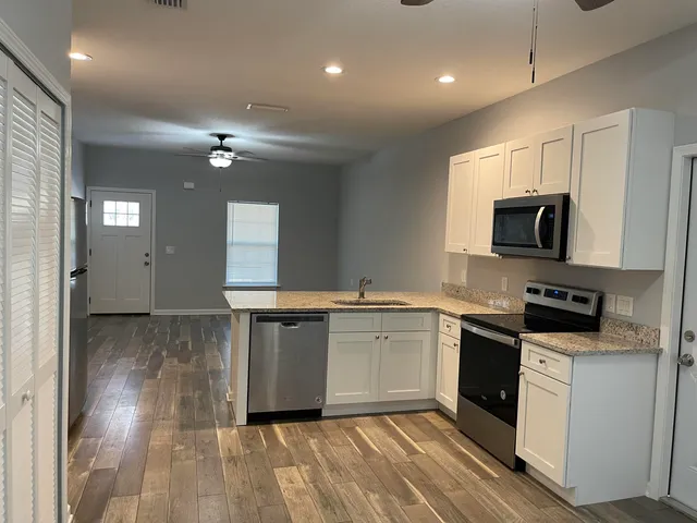 a kitchen with granite countertop a stove top oven sink and cabinets