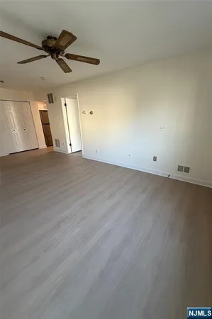 an empty room with a ceiling fan and window