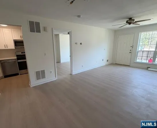 a view of a livingroom with wooden floor and a kitchen