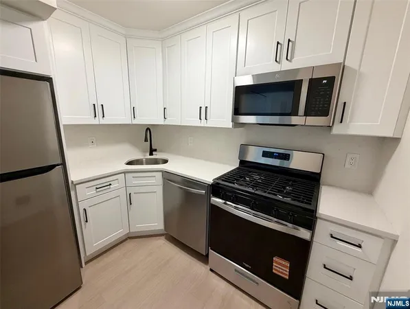 a kitchen with white cabinets and black appliances