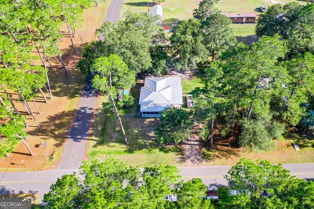 an aerial view of residential house with outdoor space and trees all around