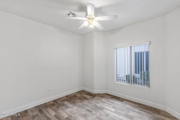 an empty room with a ceiling fan and wooden floor