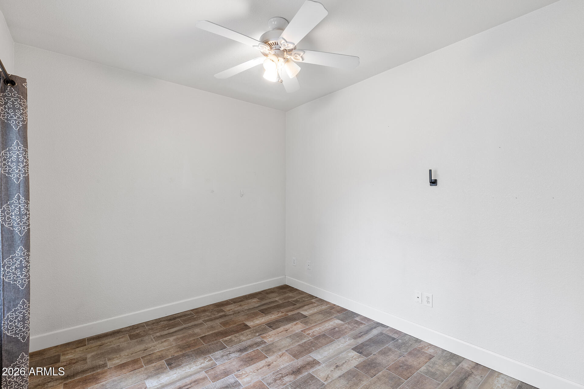 7101 West Beardsley Road, Unit 1303 Glendale, AZ 85308 - Photo 36 of 53 an empty room with a ceiling fan and wooden floor