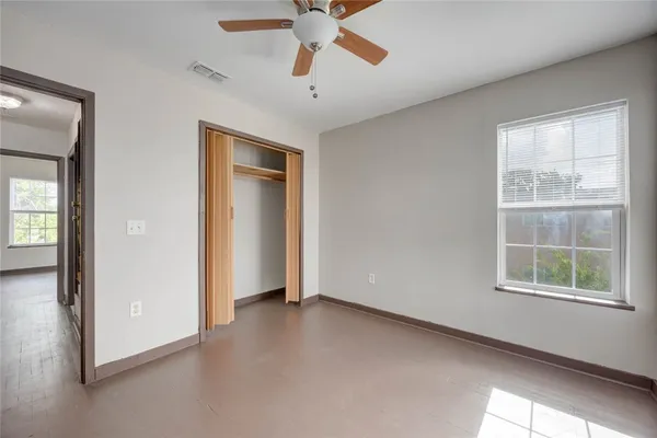 an empty room with window and a ceiling fan