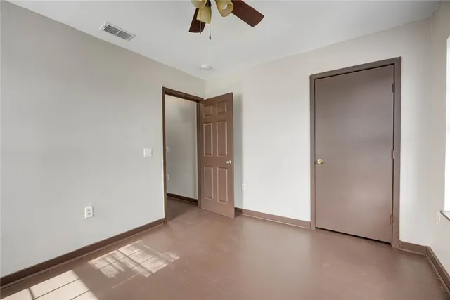 an empty room with ceiling fan and window