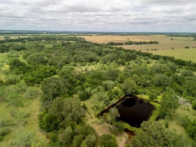a view of a field with an ocean and trees