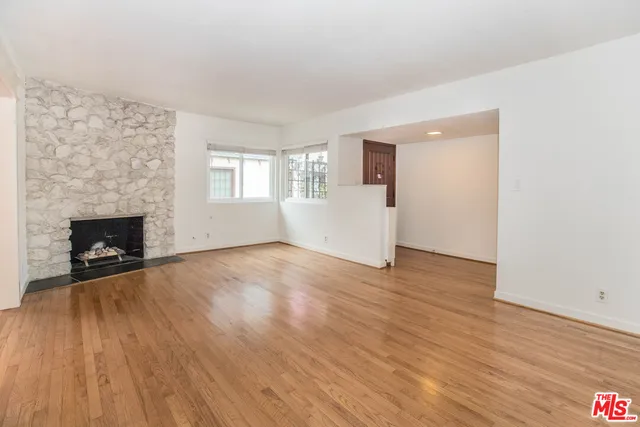 an empty room with wooden floor and fireplace