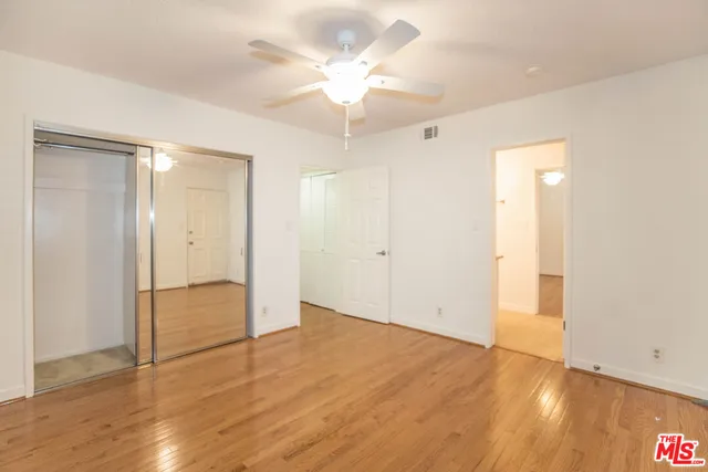 an empty room with wooden floor and a ceiling fan