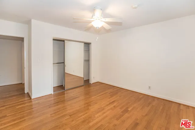 an empty room with wooden floor and a ceiling fan