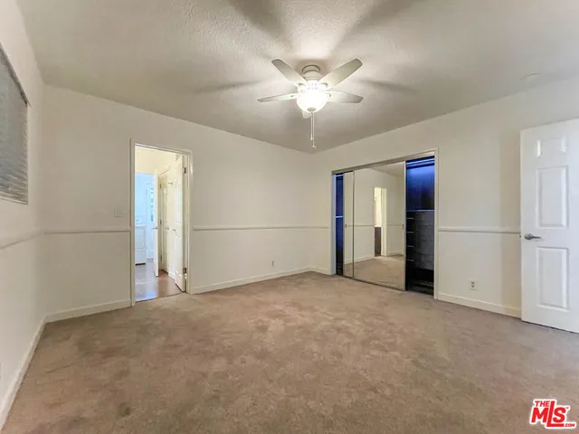 a view of an empty room with a chandelier fan