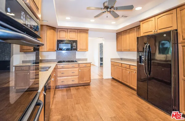 a kitchen with stainless steel appliances kitchen island granite countertop a refrigerator a stove and a sink with cabinets