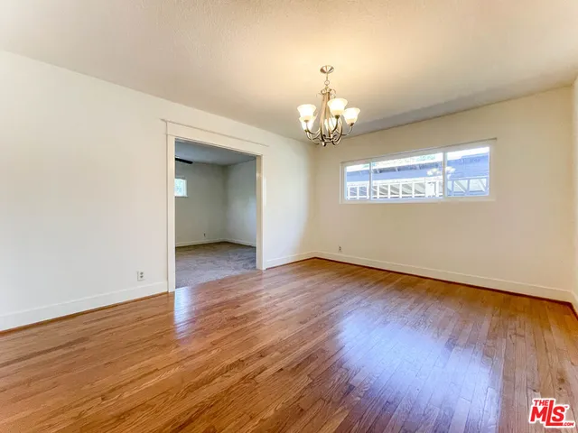 an empty room with wooden floor and chandelier